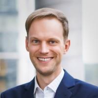 Portrait of a smiling man in a suit against a light background.