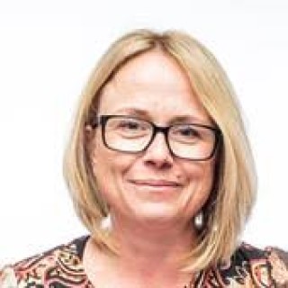 Portrait of a woman with blonde hair and glasses against a white background