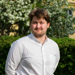 Person i vit skjorta mot grön bakgrund.