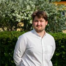 Person i vit skjorta med grönska i bakgrunden