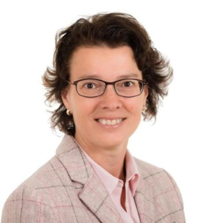 Kvinna med mörkt hår och glasögon mot vit bakgrund.